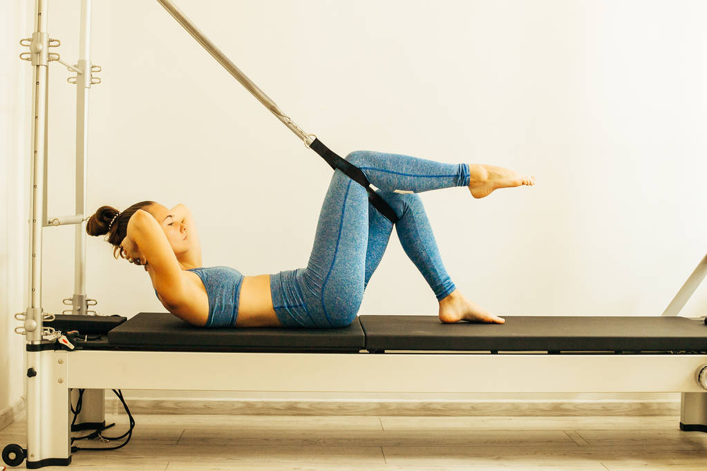 Mujer realizando ejercicio de Pilates usando una mesa Cadillac o Trapeze
 - Foto, Imagen