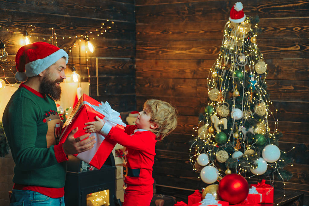 Los niños disfrutan las vacaciones de Navidad. Feliz padre e hijo decorando el árbol de Navidad. Familia navideña. La mañana antes de Navidad
. - Foto, imagen