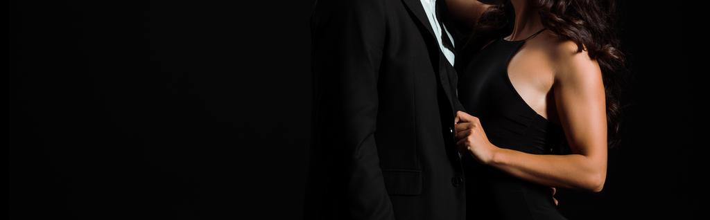 Panoramaaufnahme von Frau berührt Anzug des Mannes isoliert auf schwarz  - Foto, Bild