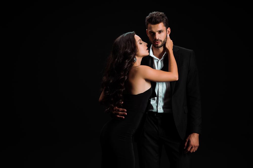 passionate girl in dress touching handsome bearded man isolated on black  - Photo, Image