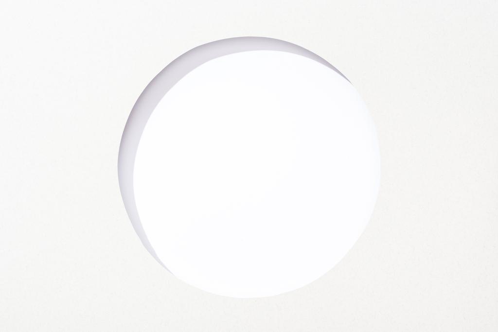 uitgesneden ronde gat in wit papier op witte achtergrond - Foto, afbeelding