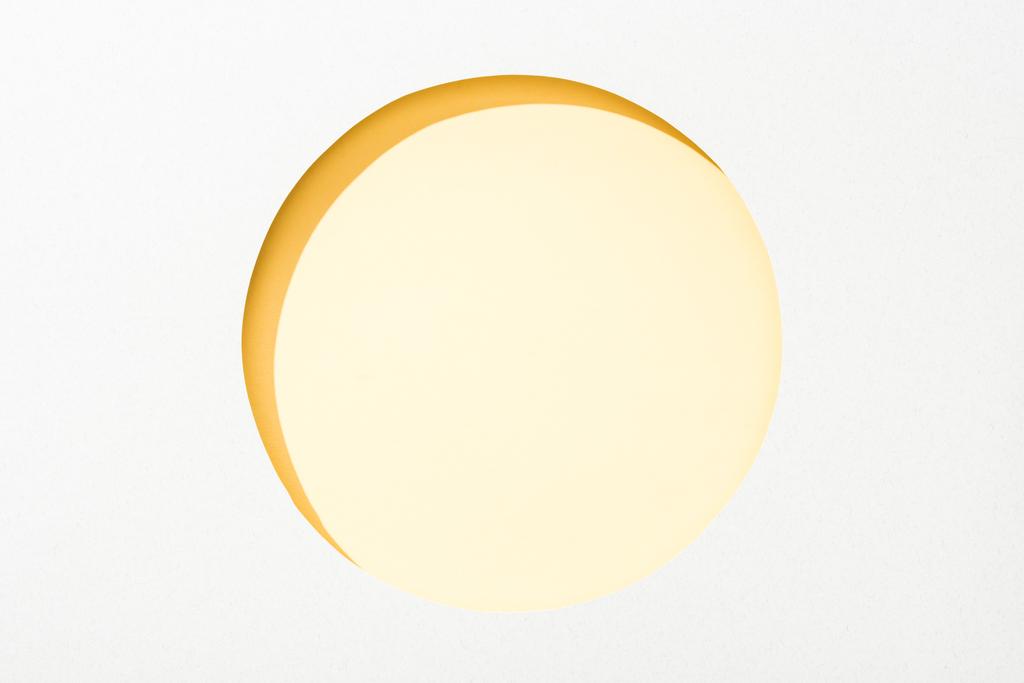 Κόψτε την στρογγυλή τρύπα σε λευκό χαρτί σε κίτρινο φόντο - Φωτογραφία, εικόνα