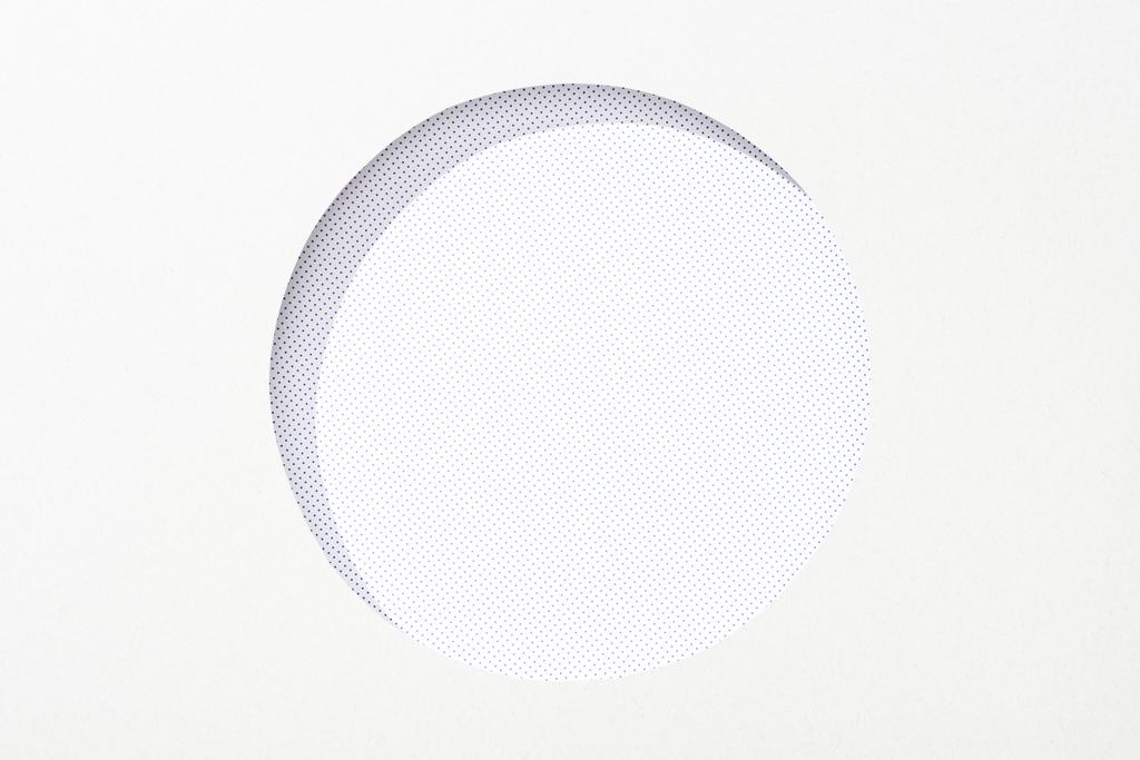 uitgesneden ronde gat in wit papier op gestippelde achtergrond - Foto, afbeelding