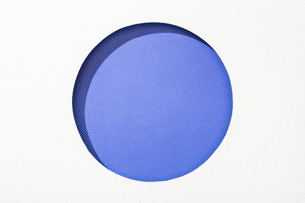 κομμένο στρογγυλό τρύπα σε λευκό χαρτί για μωβ διακεκομμένο πολύχρωμο φόντο - Φωτογραφία, εικόνα