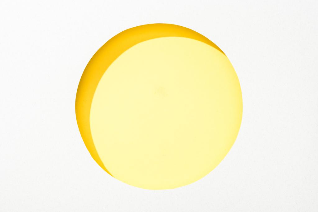 カラフルな黄色の背景に白い紙の丸い穴を切り取る - 写真・画像