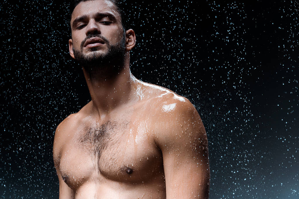 shirtless sexy man looking at camera under raindrops on black  - Photo, Image