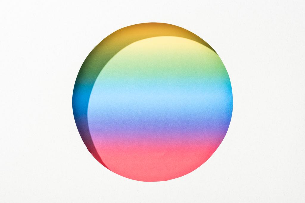 ausgeschnittene runde Loch in weißem Papier auf hellem Regenbogen bunten Hintergrund - Foto, Bild