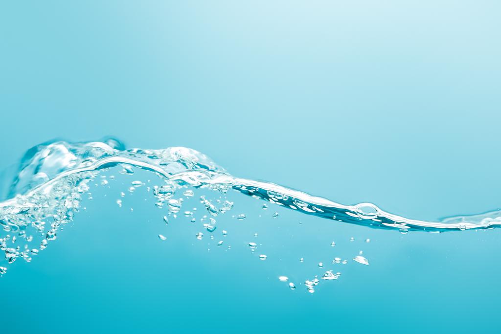 transparant zuiver golvend water met druppels op blauwe achtergrond - Foto, afbeelding