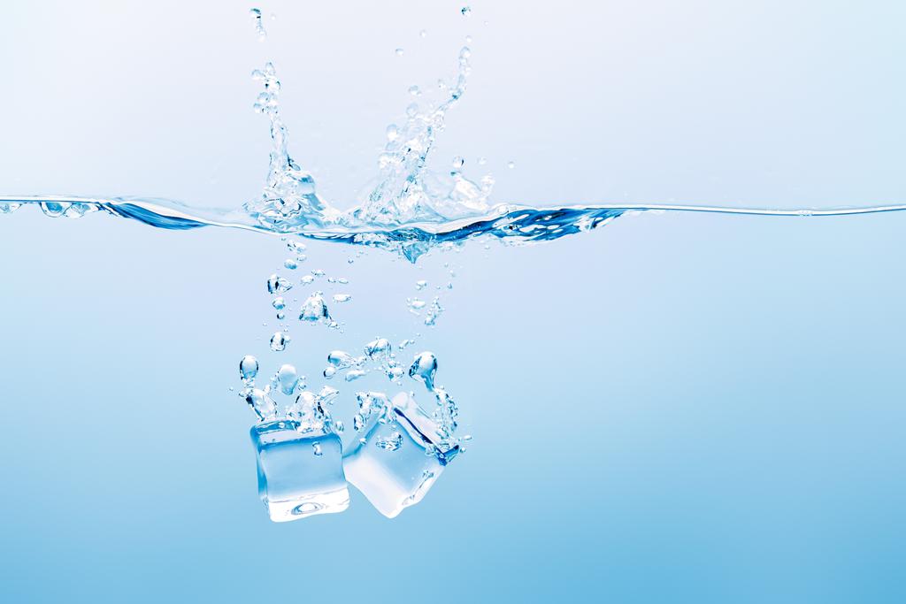 átlátszó víz, splash, buborékok és a jégkocka a kék háttér - Fotó, kép
