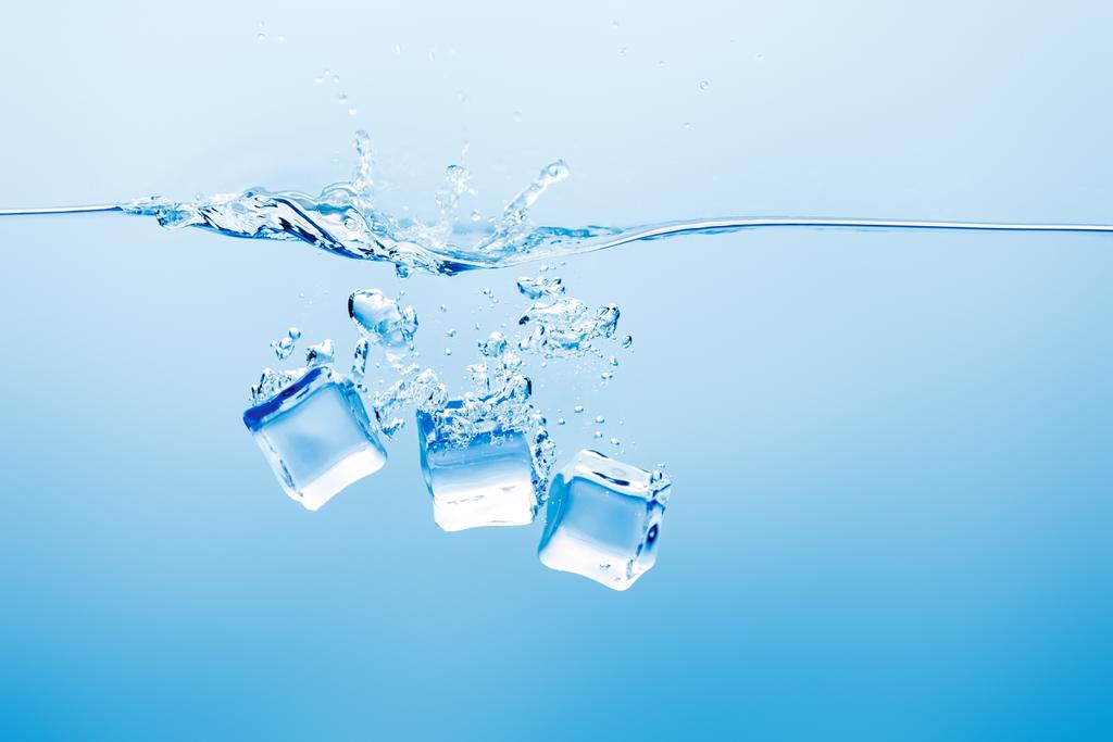 青い背景にスプラッシュと氷と透明な純水 - 写真・画像