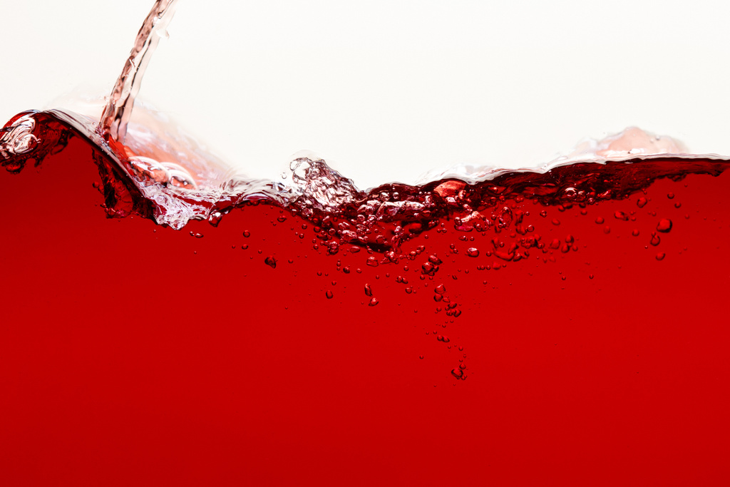 tekoucí červeně zářící tekutiny se šplouchnutím a bublinami izolovanými na bílém - Fotografie, Obrázek