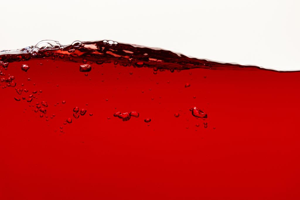 wellenförmige rote helle Flüssigkeit mit Blasen isoliert auf weiß - Foto, Bild