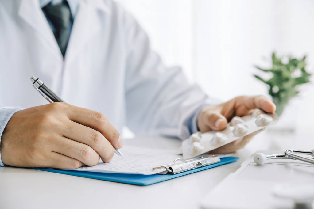 Close-up handen arts nemen pillen, tabletten en schrijven prescripti - Foto, afbeelding