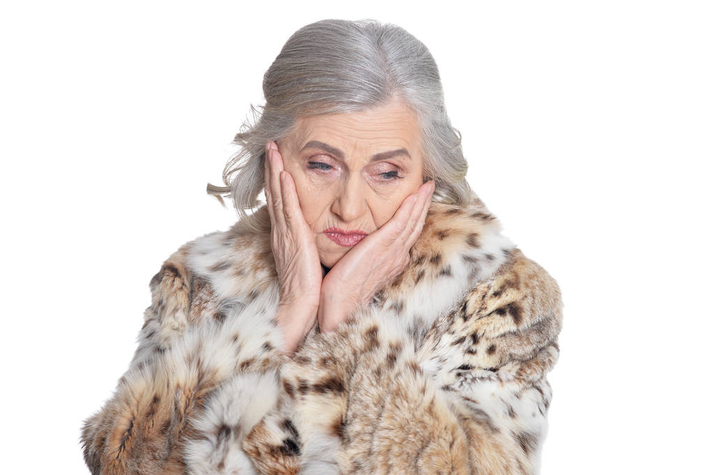 Porträt einer traurigen schönen Seniorin im Pelzmantel, die vor weißem Hintergrund posiert - Foto, Bild