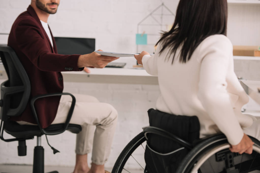 cropped view of disabled businesswoman giving documents to colleague in office - Photo, Image