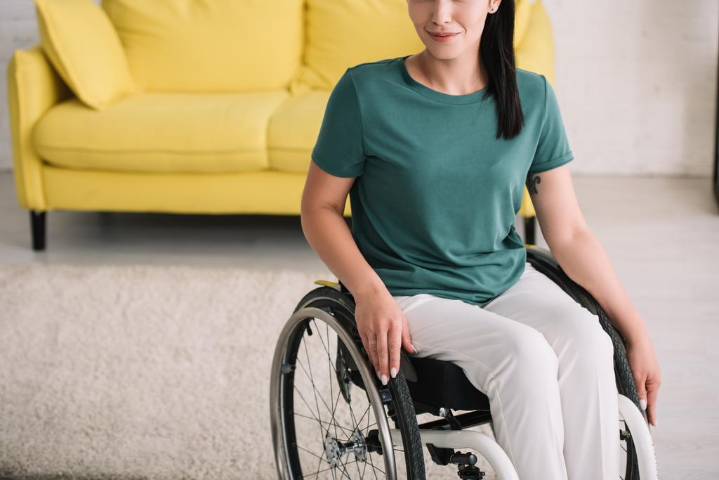 自宅で車椅子に座っている笑顔の障害者女性のトリミングされたビュー - 写真・画像