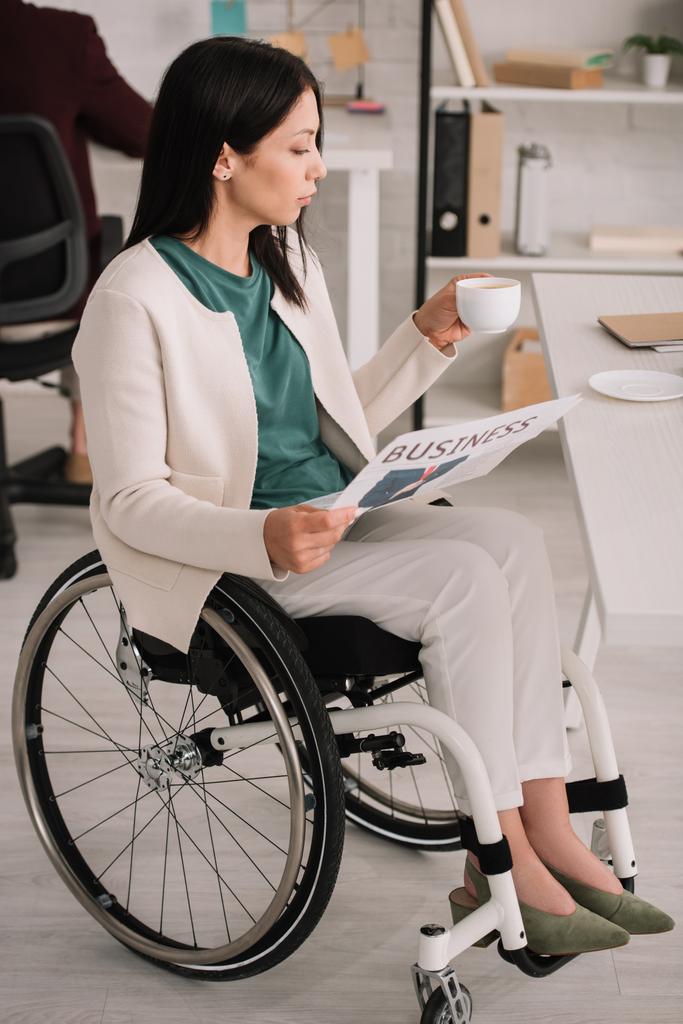 tekerlekli sandalyede işyerinde otururken güzel engelli iş kadını - Fotoğraf, Görsel