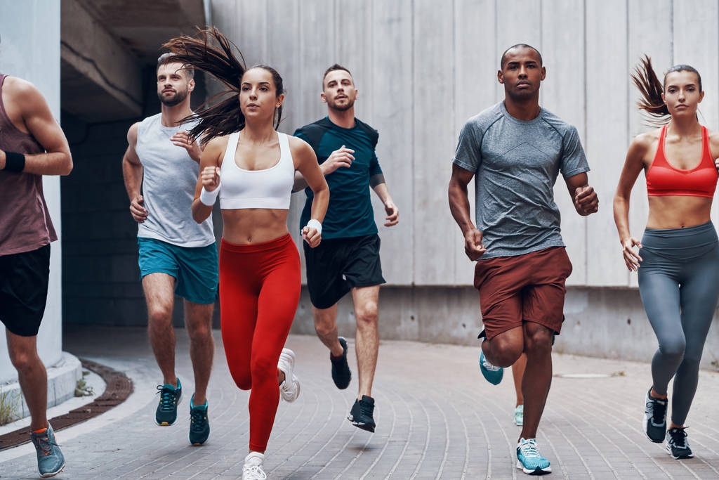 Grupo de jóvenes en ropa deportiva corriendo en la calle de la ciudad
  - Foto, imagen