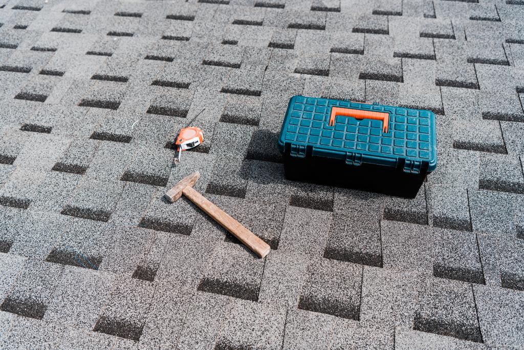коробка інструментів біля молотка і вимірювальна стрічка на даху
  - Фото, зображення
