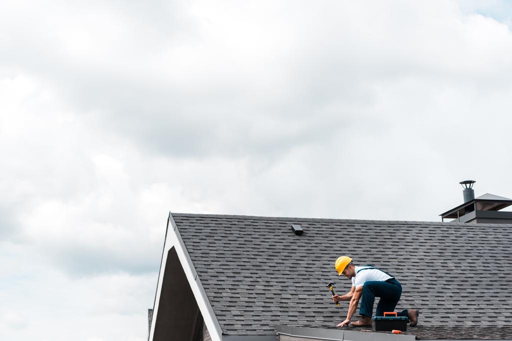 ремонтник у шоломі тримає молоток під час ремонту даху
  - Фото, зображення