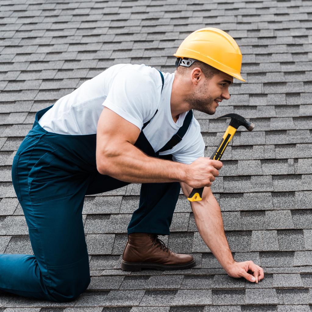 ремонтник в шлеме держит молоток во время ремонта крыши в доме
  - Фото, изображение