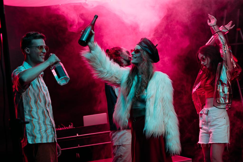 чоловіки і дівчата з алкоголем танцюють в нічному клубі з рожевим димом
 - Фото, зображення