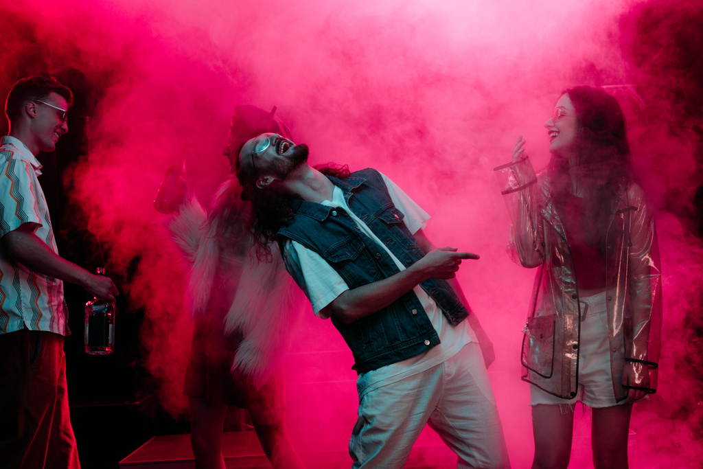 Männer und Mädchen tanzen in Nachtclub mit rosa Rauch - Foto, Bild