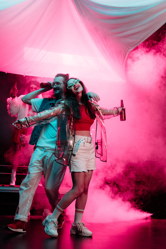 happy man and beautiful girl dancing in nightclub with pink smoke - Photo, Image