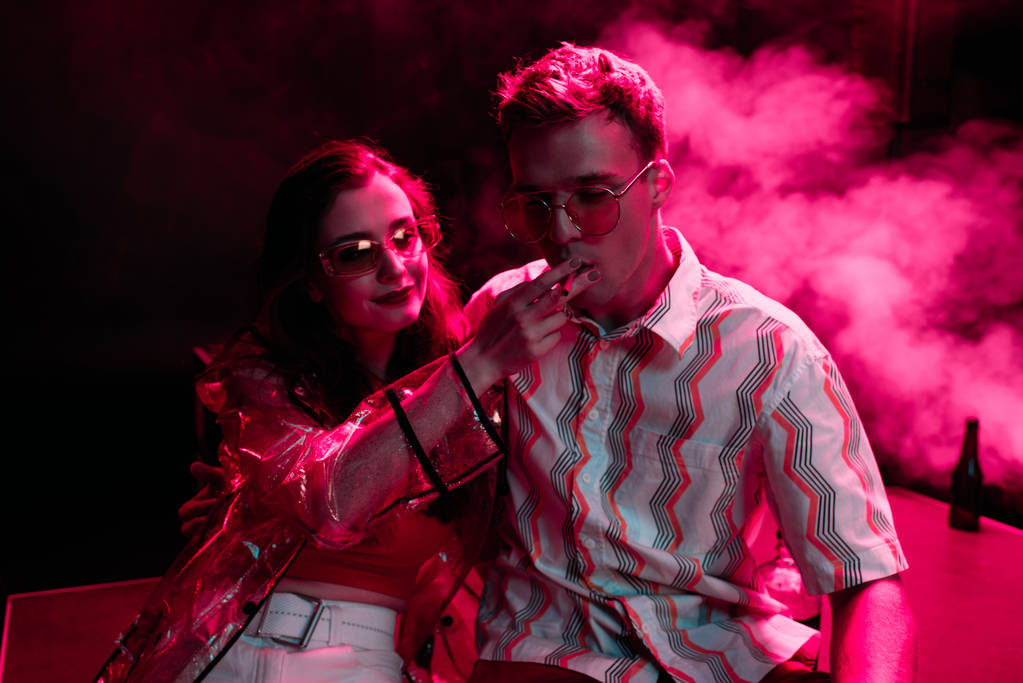 Mann raucht Zigarette neben junger Frau bei Rave-Party in Nachtclub - Foto, Bild