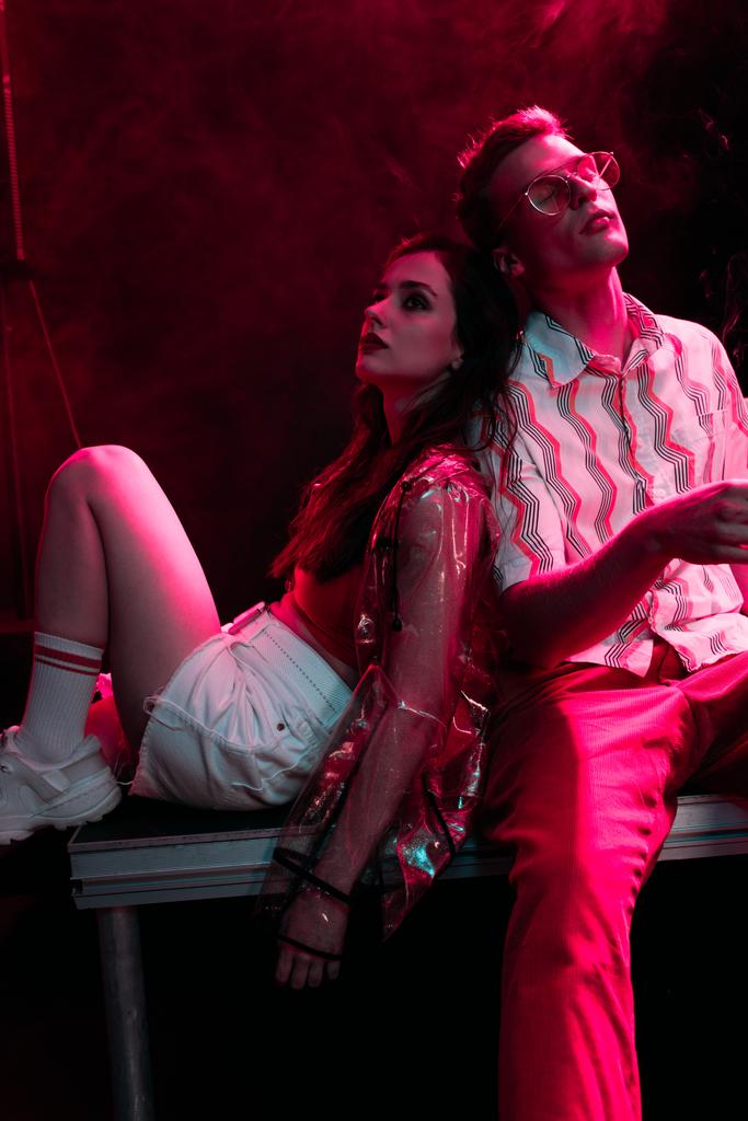 άντρας και νεαρή γυναίκα κάθονται μαζί κατά τη διάρκεια ρέιβ πάρτι σε νυχτερινό κέντρο διασκέδασης - Φωτογραφία, εικόνα