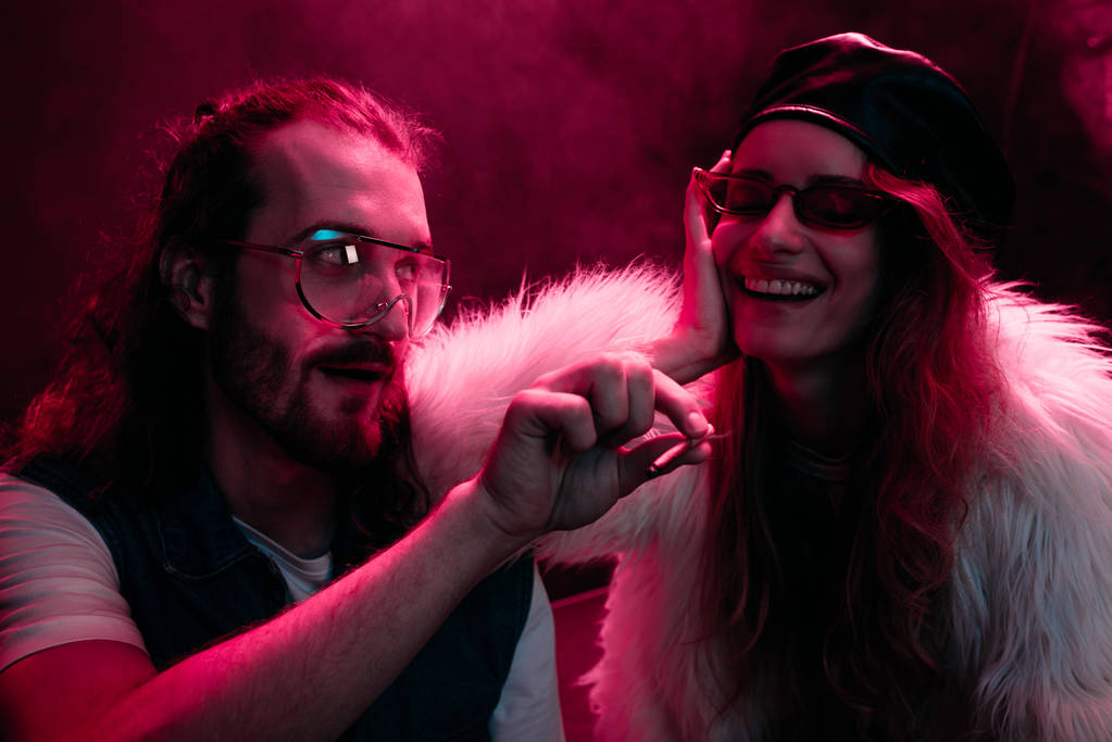 man giving marijuana joint to smiling girl in nightclub - Photo, Image