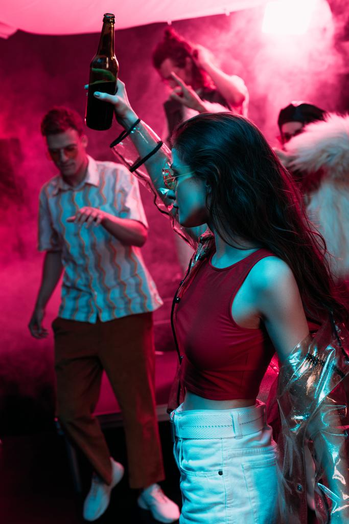 schönes Mädchen mit Bier in der Hand und Tanz in einem Nachtclub mit neonrosa Rauch - Foto, Bild