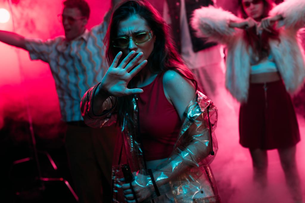 ピンクの煙でナイトクラブで踊っている間、手でジェスチャーする女の子 - 写真・画像