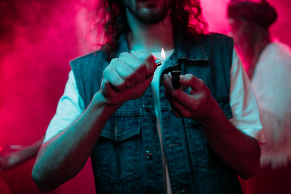 cropped view of man lighting smoking pipe with marijuana in nightclub - Photo, Image