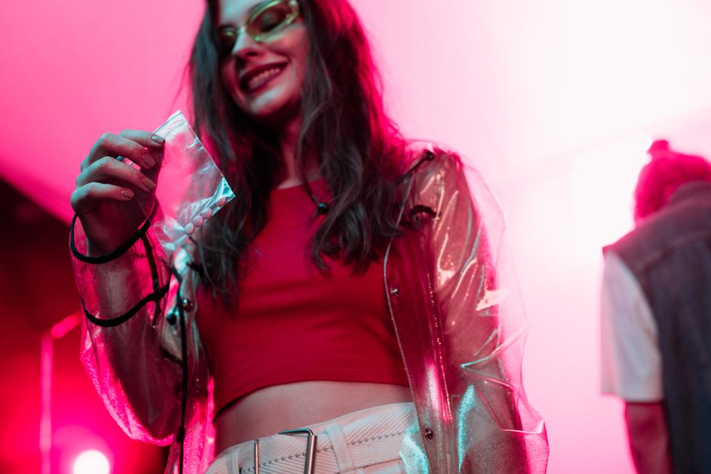 usměvavá dívka držící plastikový zip sáček s drogami v nočním klubu - Fotografie, Obrázek