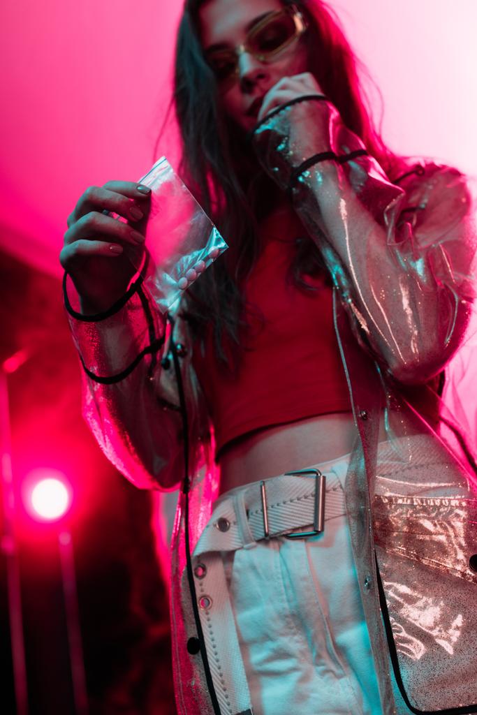 девушка держит пластиковый пакет молнии с наркотиками в ночном клубе
 - Фото, изображение
