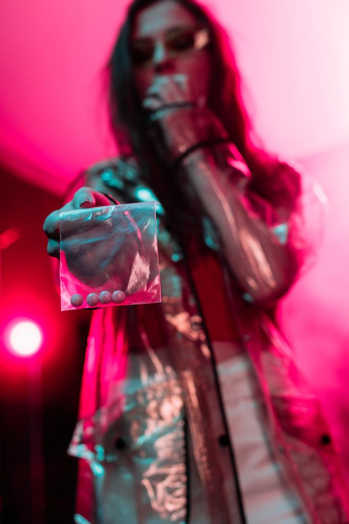 fille tenant sac à glissière en plastique avec des drogues dans la boîte de nuit, foyer sélectif
 - Photo, image
