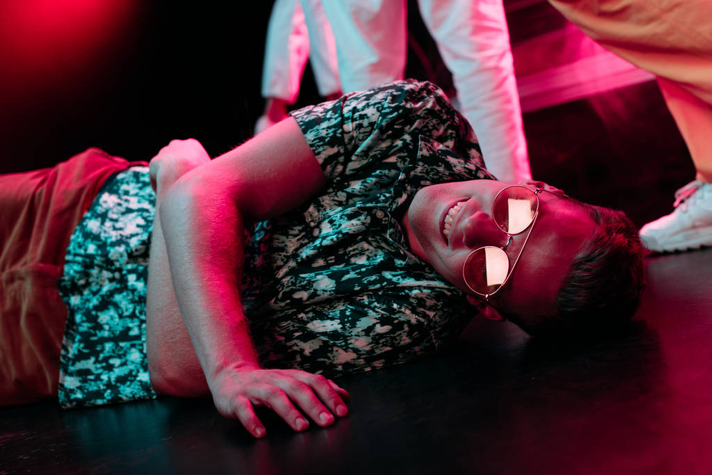 больной в солнечных очках лежит на полу в ночном клубе
  - Фото, изображение