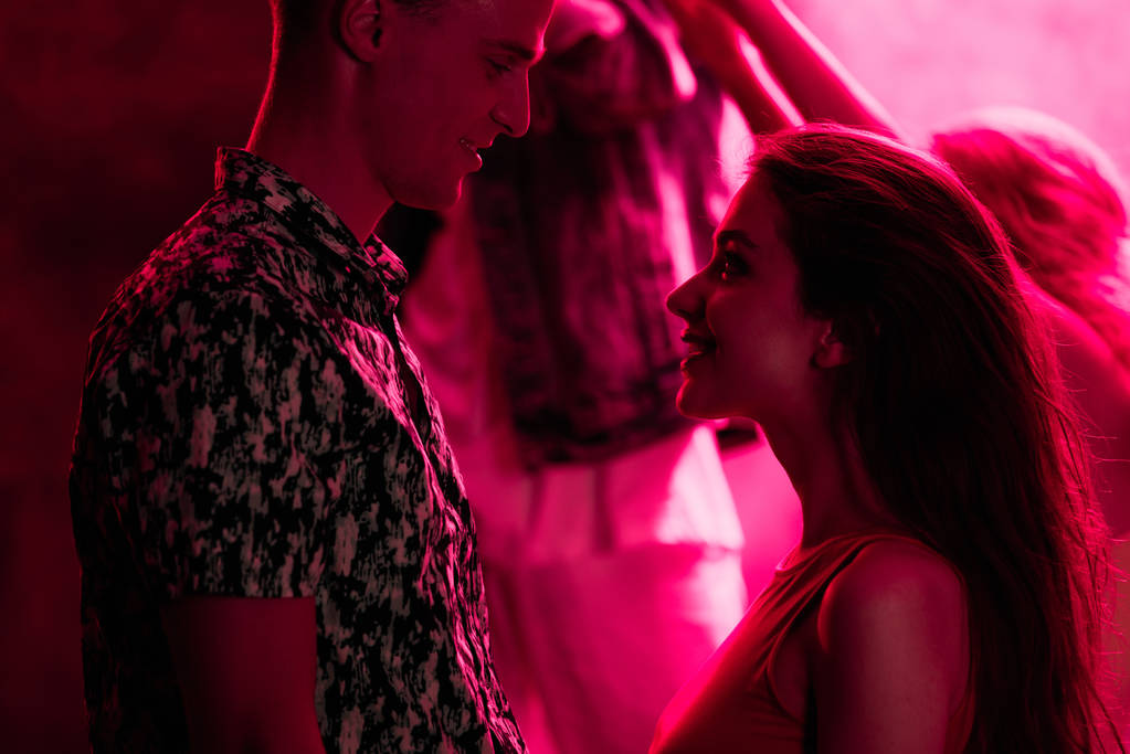 άνθρωπος κοιτάζοντας νέα γυναίκα κατά τη διάρκεια ρέιβ πάρτι σε νυχτερινό κέντρο διασκέδασης - Φωτογραφία, εικόνα