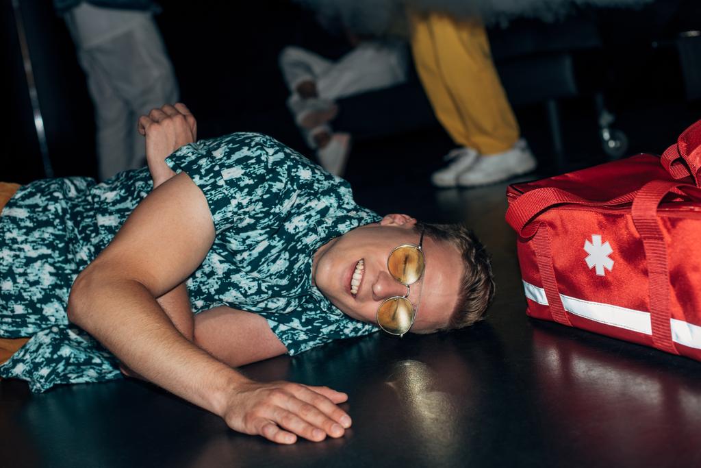hombre acostado en el suelo cerca de la bolsa de kit de primeros auxilios en discoteca
 - Foto, Imagen