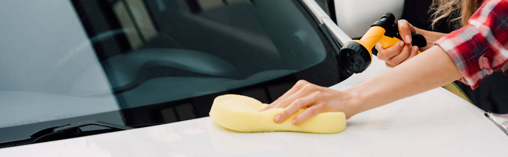 panoramiczny strzał młodej kobiety trzyma gąbkę podczas mycia samochodu  - Zdjęcie, obraz