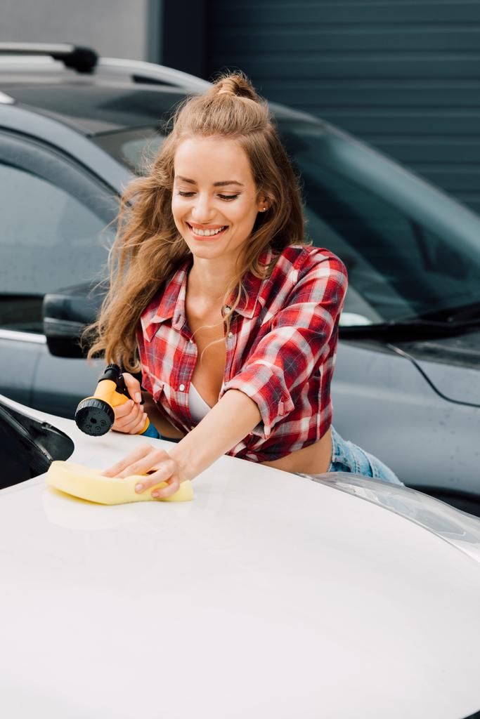 車を洗っている間、圧力洗濯機とスポンジを保持する幸せな女の子  - 写真・画像