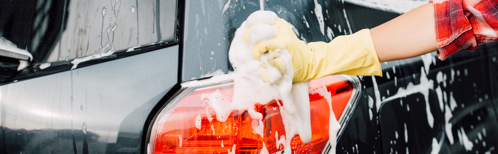 πανοραμικό σφηνάκι κορίτσι με γάντι λατέξ κοντά σε βρεγμένο αυτοκίνητο σε αφρό  - Φωτογραφία, εικόνα