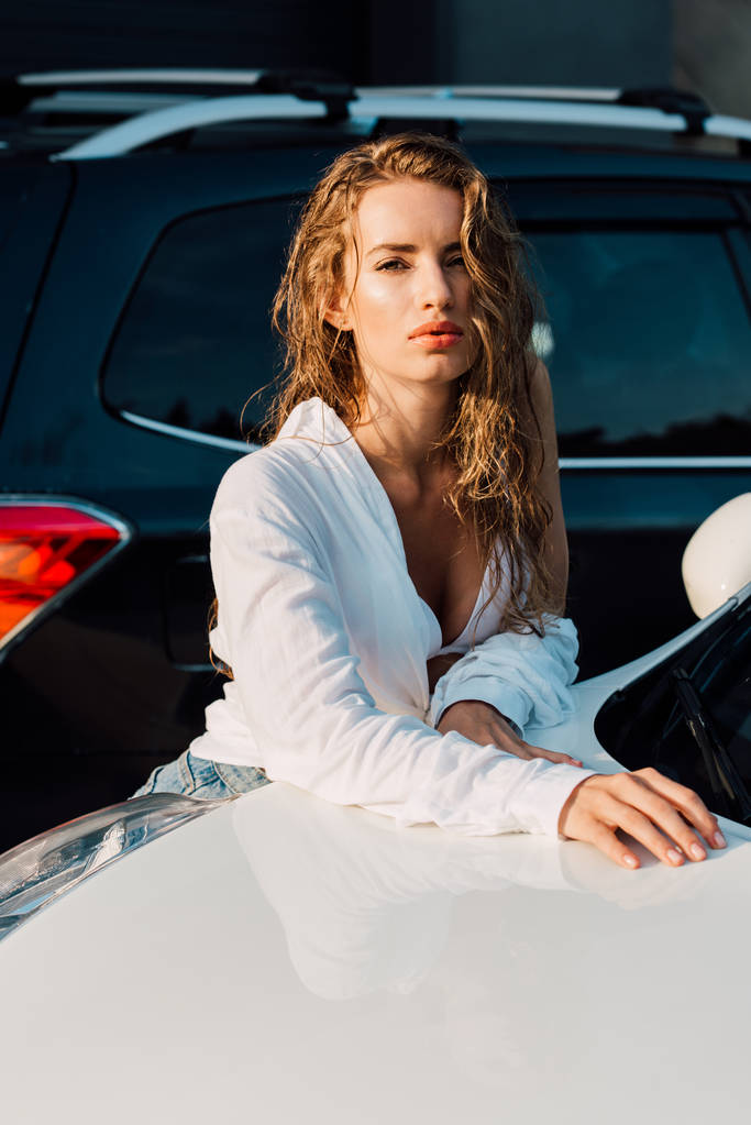 sexy jonge vrouw kijken naar camera in de buurt van witte auto  - Foto, afbeelding