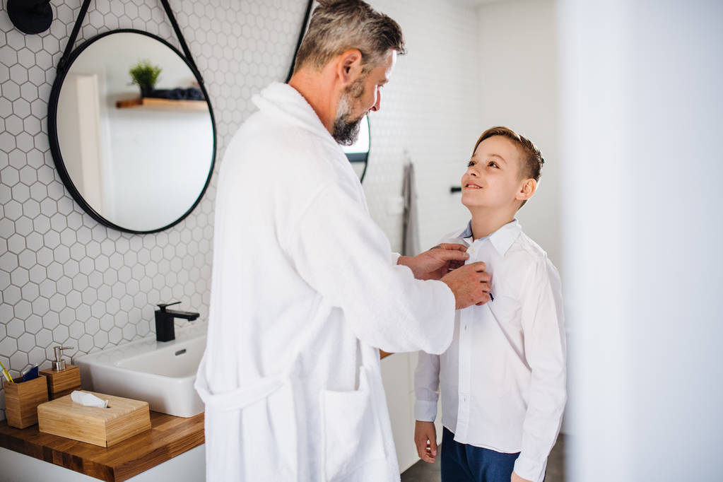 Mature father with small son getting dressed in the bathroom in the morning. - Photo, Image