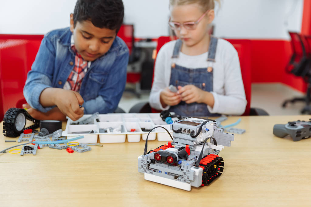 Gemengde rassengroep school kinderen zitten in de klas met DIY robot, stem onderwijsconcept. - Foto, afbeelding