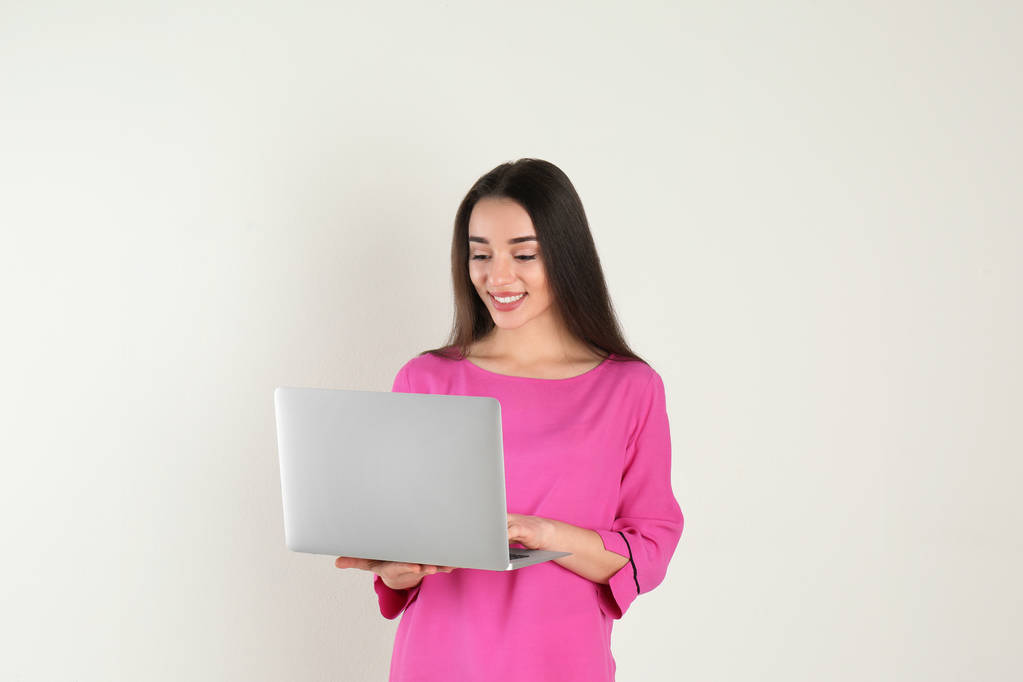 Portré a fiatal nő alkalmi ruhában a laptop a világos háttér - Fotó, kép