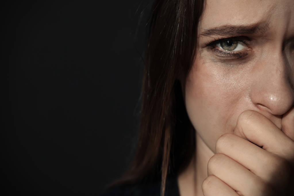 Плачущая молодая женщина на тёмном фоне, место для смс. Остановить насилие
 - Фото, изображение