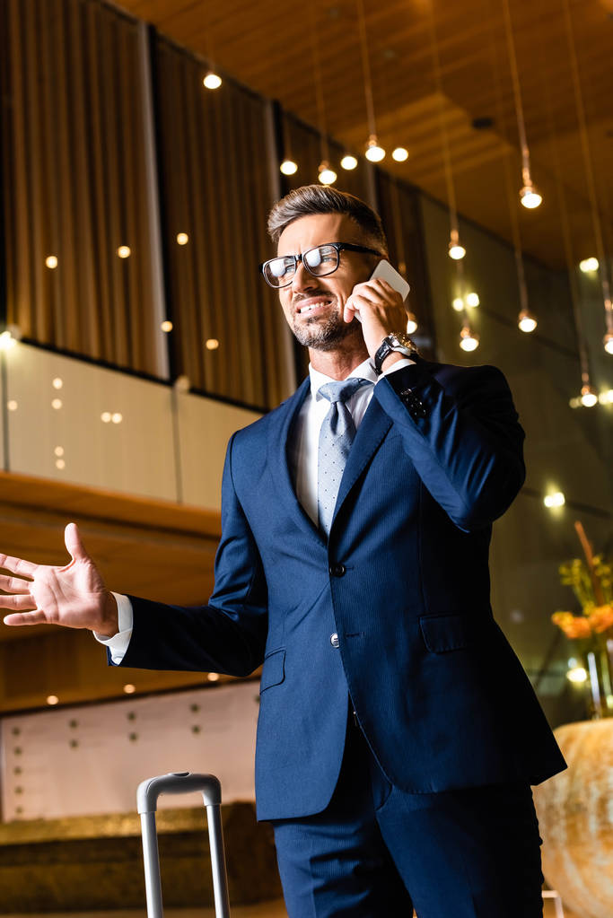 homem de negócios bonito em terno e óculos falando no smartphone
  - Foto, Imagem