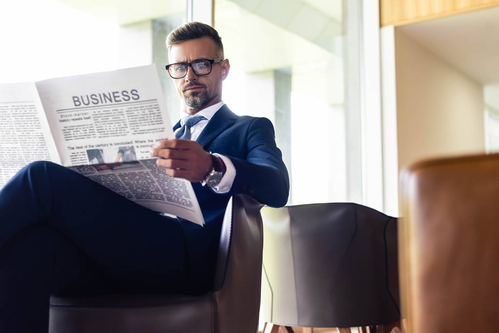 красивый бизнесмен в костюмах и очках, читающий газетный бизнес
 - Фото, изображение